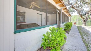 A covered porch with a ceiling fan, a window with a view of the interior, and a pathway leading to a body of water. - Lanai & Fire Pit: Riverfront Studio in Chiefland! (Chiefland)