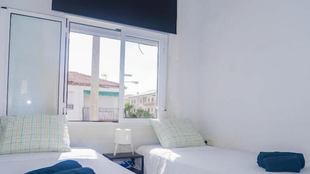 A hotel room with two beds, a window, and a view of buildings outside.