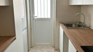 A small kitchen with a sink, a door with a window, and light-colored cabinets.