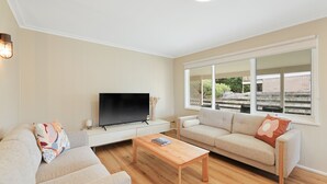 A living room with a flat-screen TV, two sofas, a coffee table, and a large window offering a view of the outside. - Avalon Cape Woolamai (Cape Woolamai)