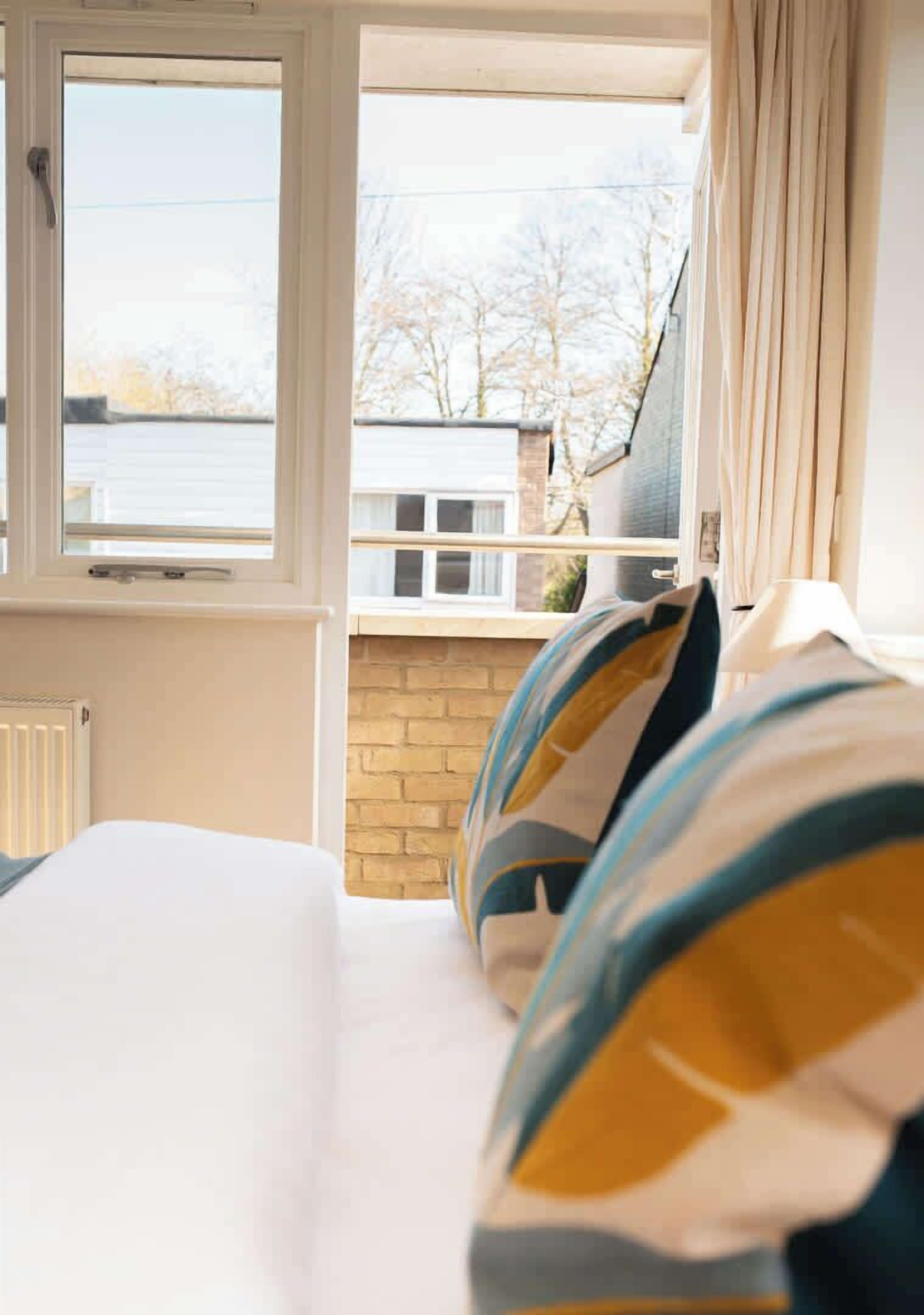 A bedroom with a bed, a window, and a view of a building and trees.
