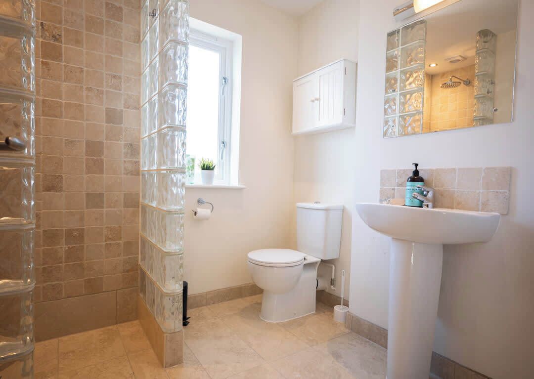 A bathroom with a toilet, sink, and glass shower enclosure.