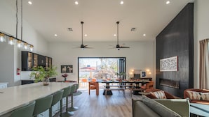 A modern kitchen with a bar area, seating, and a fireplace. - Bespoke Playhaus of Scottsdale: Open Sky Estate (Scottsdale)