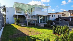 A modern two-story house with a covered patio, a staircase, and a well-maintained lawn. - Bunkhouse Koh Phangan (Ko Pha-ngan)