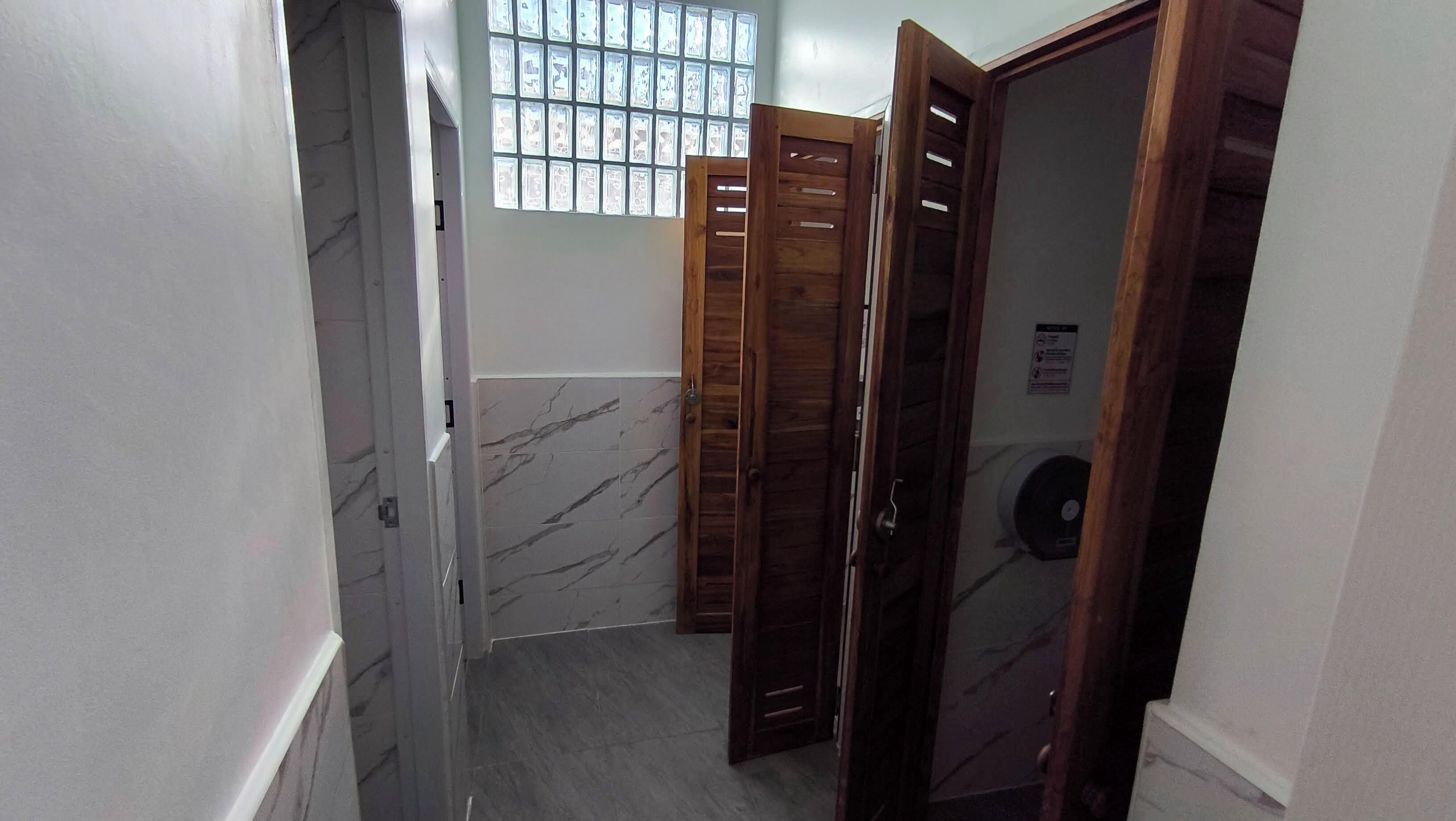 Un passadís estret amb parets de marbre, portes de fusta i una finestra amb reixes.