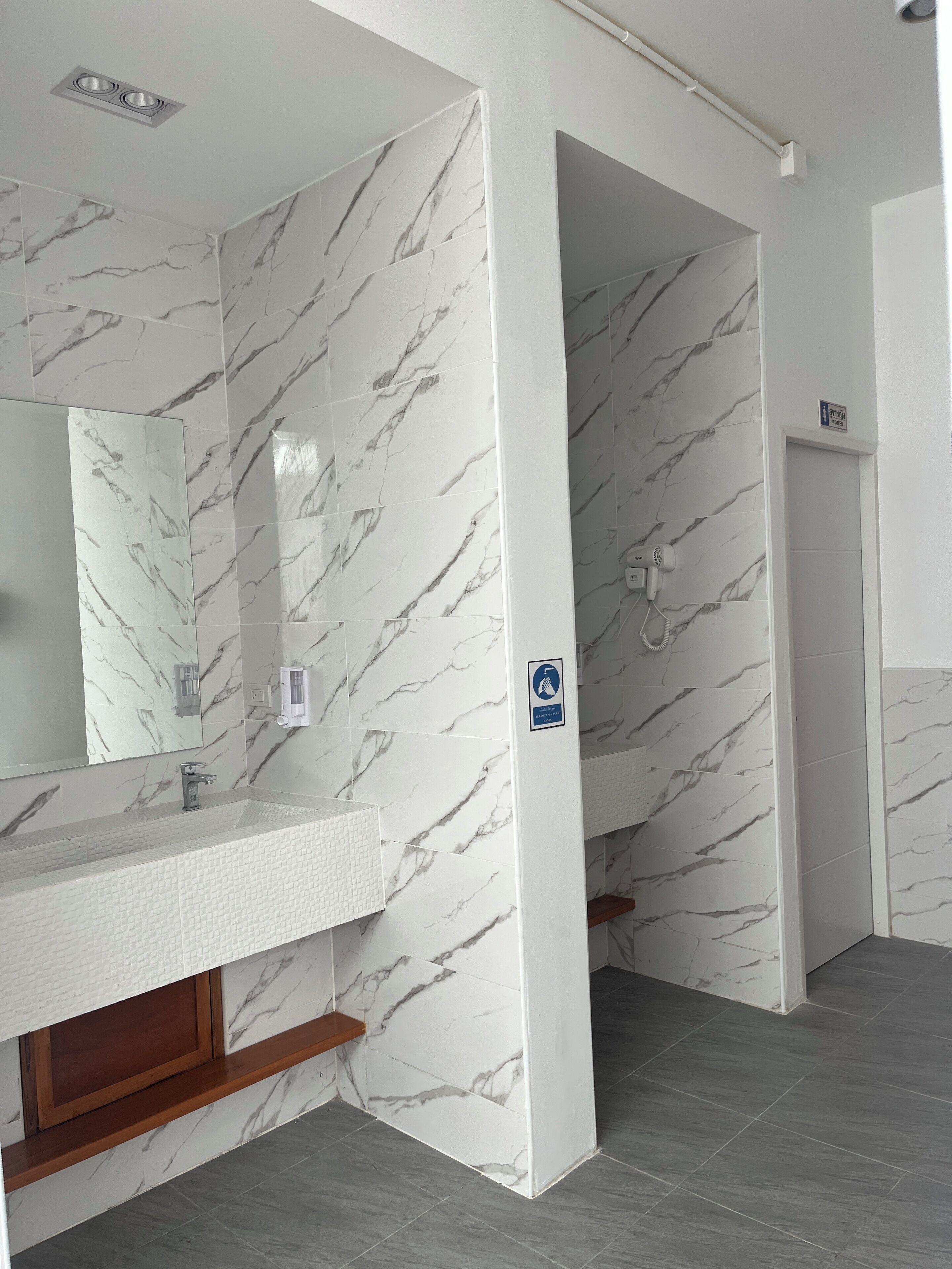 A modern bathroom with marble walls, a sink, and a shower area.