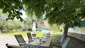 An outdoor dining area with a table and chairs, surrounded by trees and a stone wall. - Country House / Farm House in Vecchiano-nodica with 1 bedrooms sleeps 3 (Vecchiano-nodica)