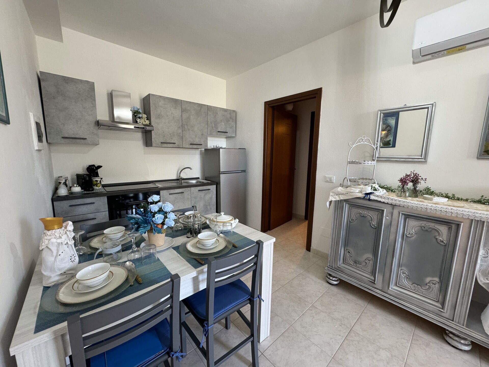 A modern kitchen with grey cabinets, a dining table set for four, and a small island with a sink.