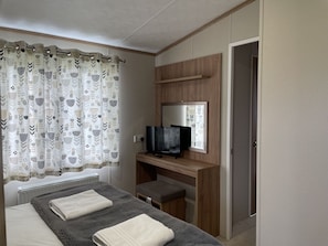 Ein Schlafzimmer mit einem Bett, einem Fernseher, einem Schreibtisch und einem Stuhl.