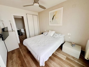 A bedroom with a bed, nightstand, and a ceiling fan.