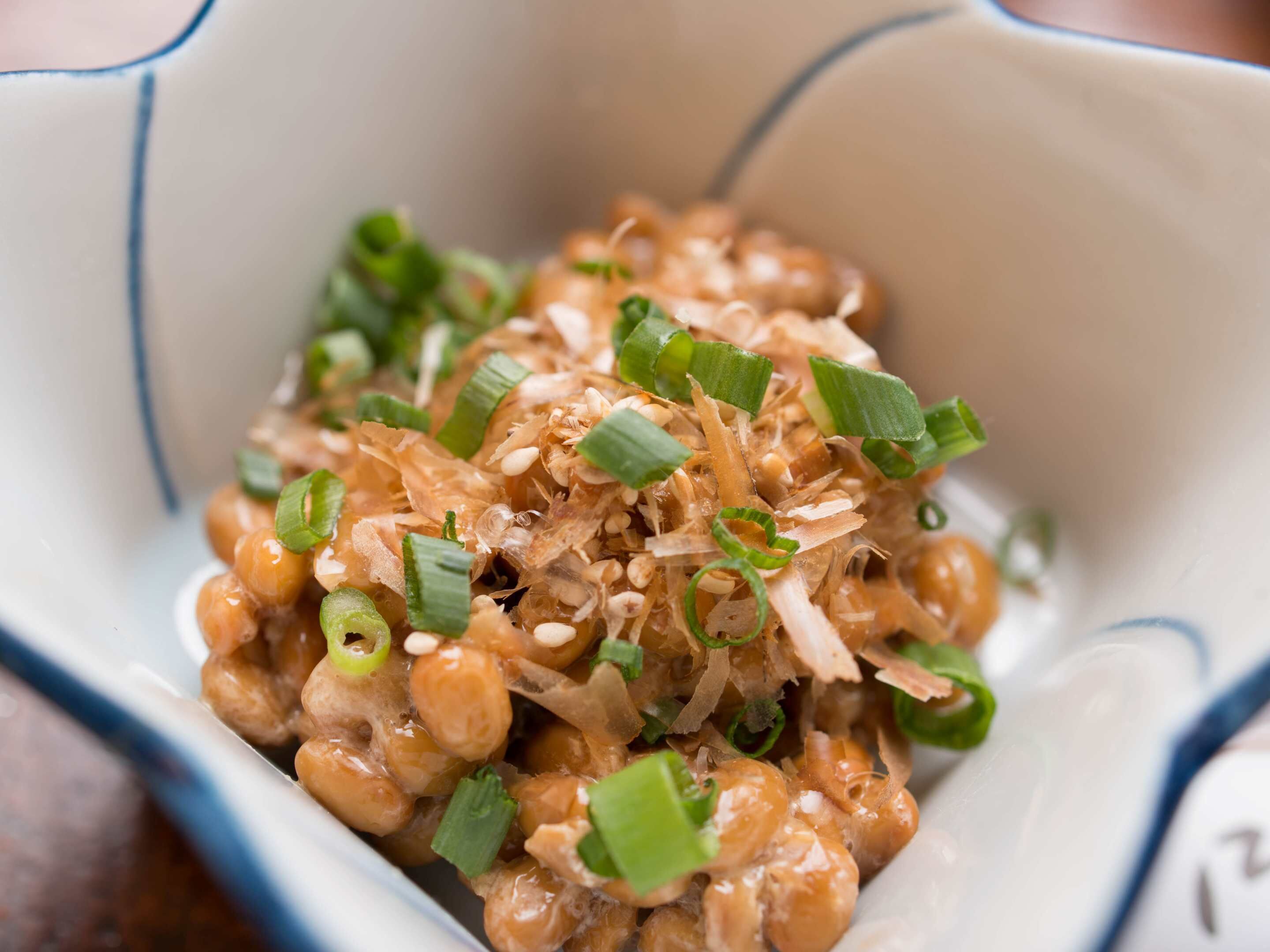 A bowl of food with green onions and sesame seeds.
