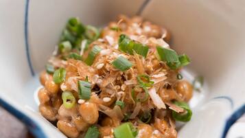A bowl of food with green onions and sesame seeds.