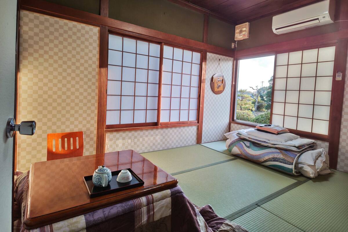 A traditional Japanese room with tatami flooring, shoji screens, and a futon bed.