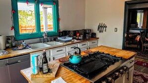 Una cocina con una isla central, estufa y fregadero. Hay diversos electrodomésticos y utensilios de cocina en las encimeras.