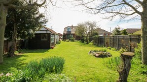 Un jardin bien entretenu, avec une pelouse, diverses plantes et une clôture en bois.