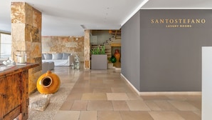 Un interior moderno con una pared de acento de piedra, un mostrador de recepción y una escalera que conduce a pisos superiores.
