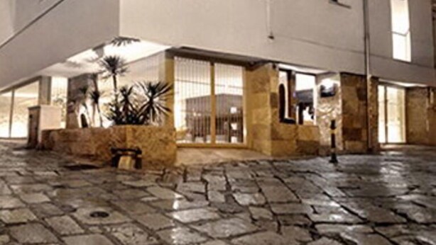 Un edificio moderno con techo plano, ventanas amplias y un patio empedrado de piedra.