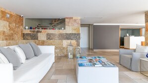 A modern living room with a stone accent wall, a white sofa, a coffee table with magazines, and a reception desk in the background.