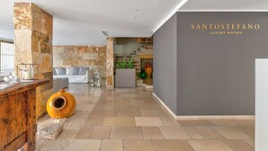 Un interior moderno con una pared de acento de piedra, un mostrador de recepción y una escalera que conduce a pisos superiores.