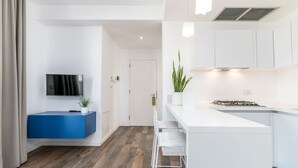 Una cocina moderna con armarios blancos, estufa integrada y una barra con taburetes.