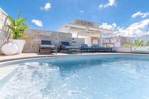 Une piscine avec des chaises longues et une pergola.