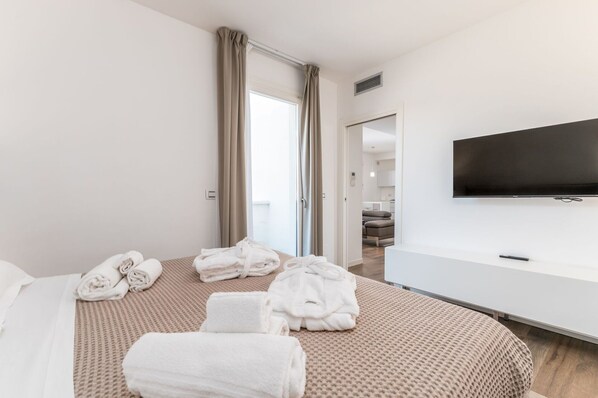 A hotel room with a bed, a TV, and a view of the living area.