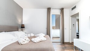 Una habitación de hotel moderna con una cama grande, una lámpara de noche, un balcón con cortinas y un baño con espejo.