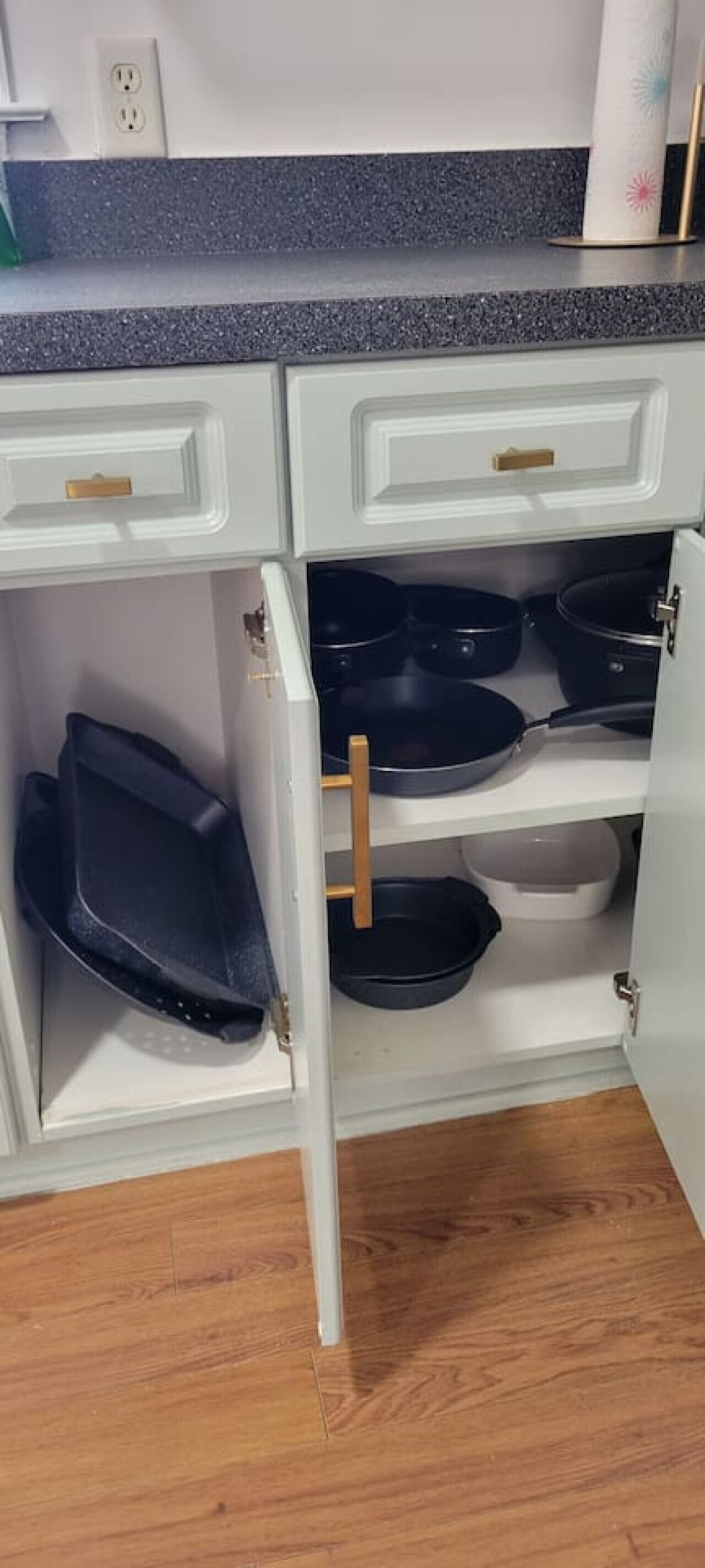 Una cocina con armarios blancos, encimera de granito y estante empotrado para ollas.