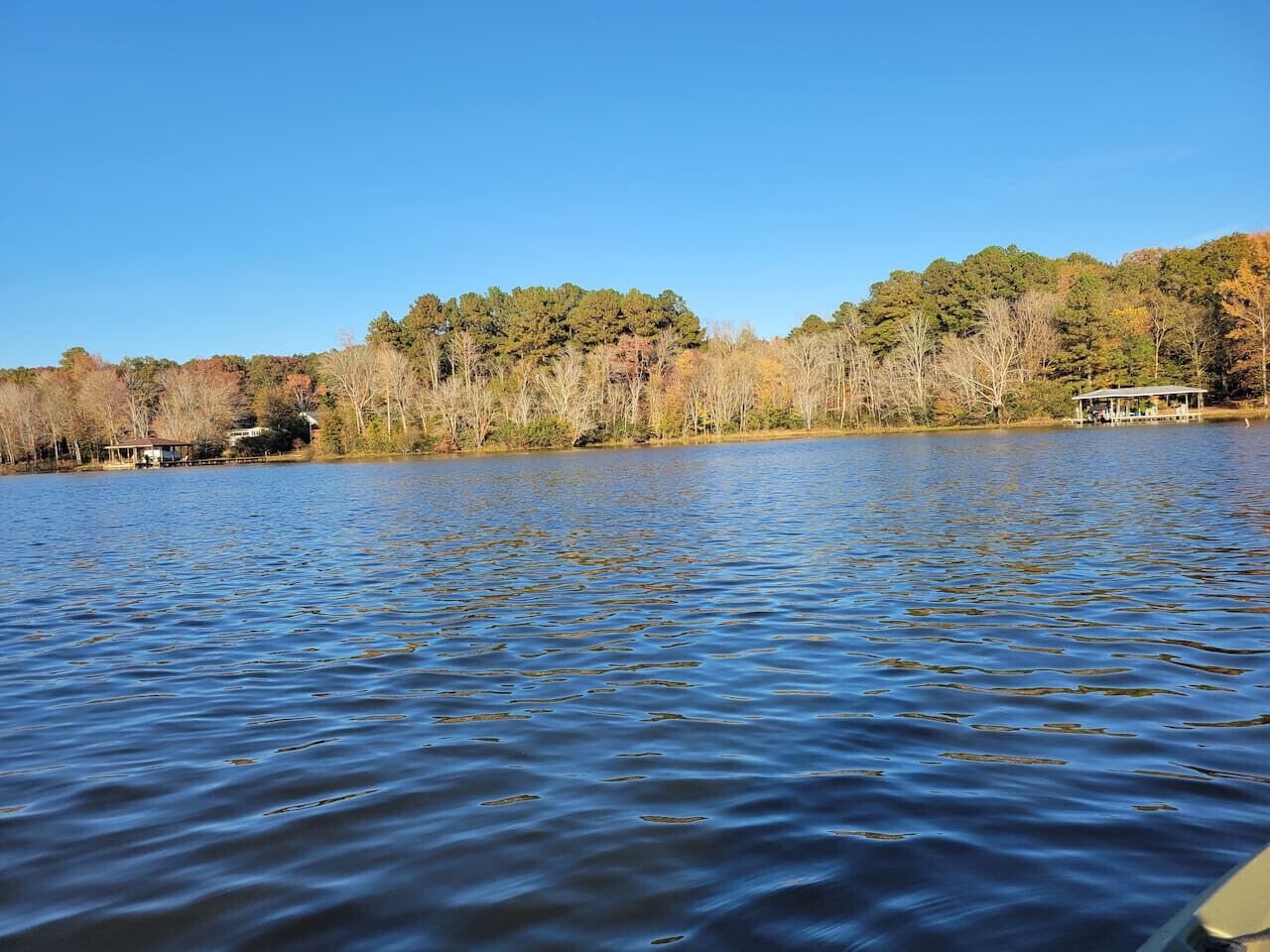 A calm lake with a dock and a small building on the shore.