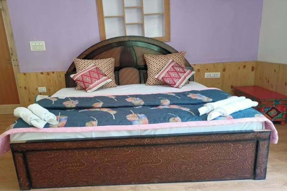 A bed with a floral-patterned bedspread, two decorative pillows, and a wooden headboard.