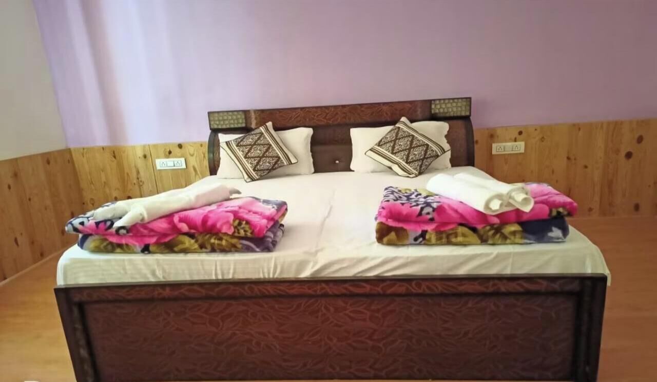 A bed with a wooden headboard, two pillows, and a blanket with a floral pattern.