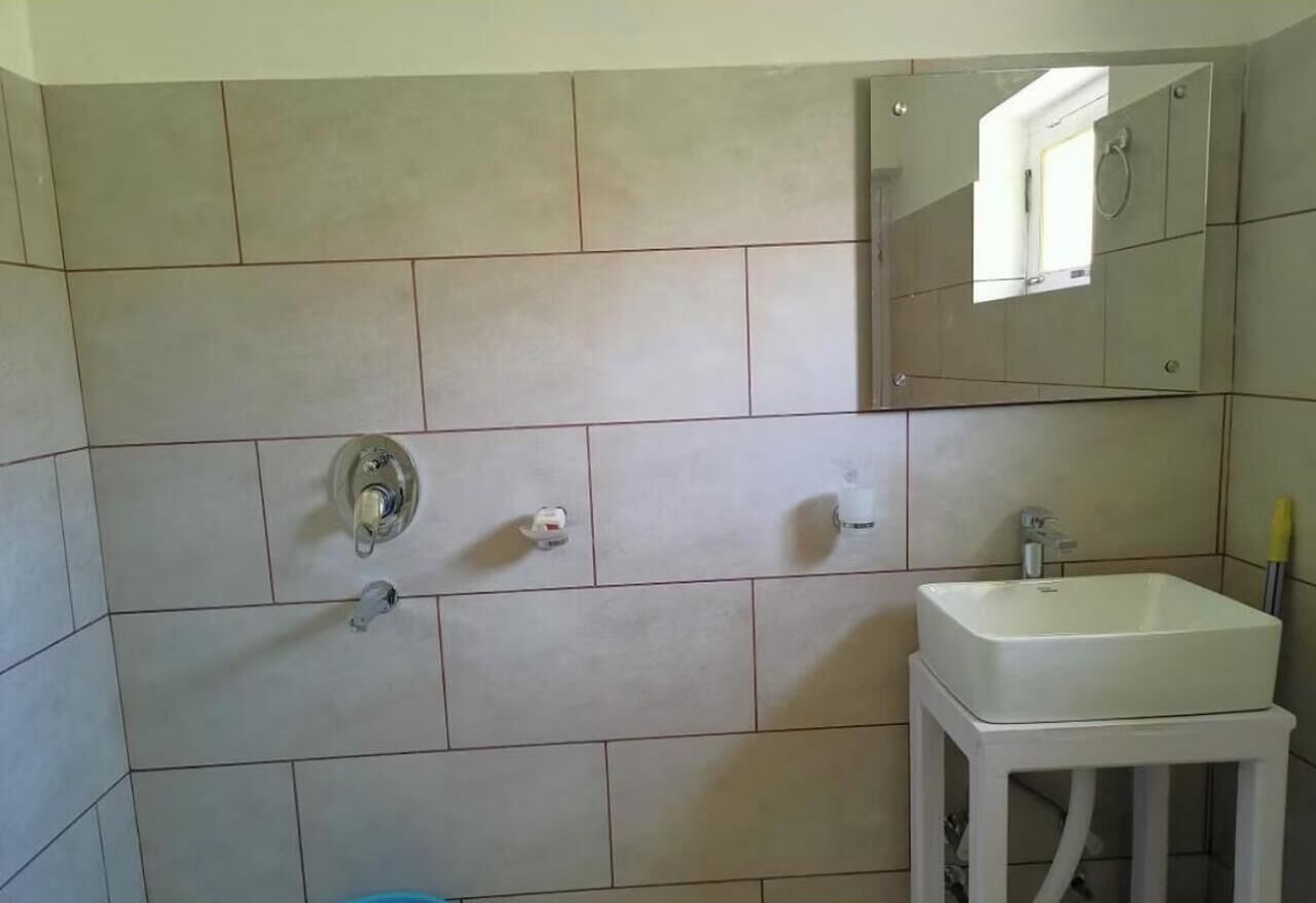 A bathroom with a white sink, a mirror, and a shower.