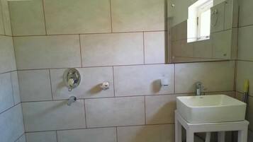 A bathroom with a white sink, a mirror, and a shower.