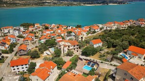 A coastal residential area with houses featuring red-tiled roofs and a clear view of the sea. - Sun Spalato Villa Alisa (Mastrinka)