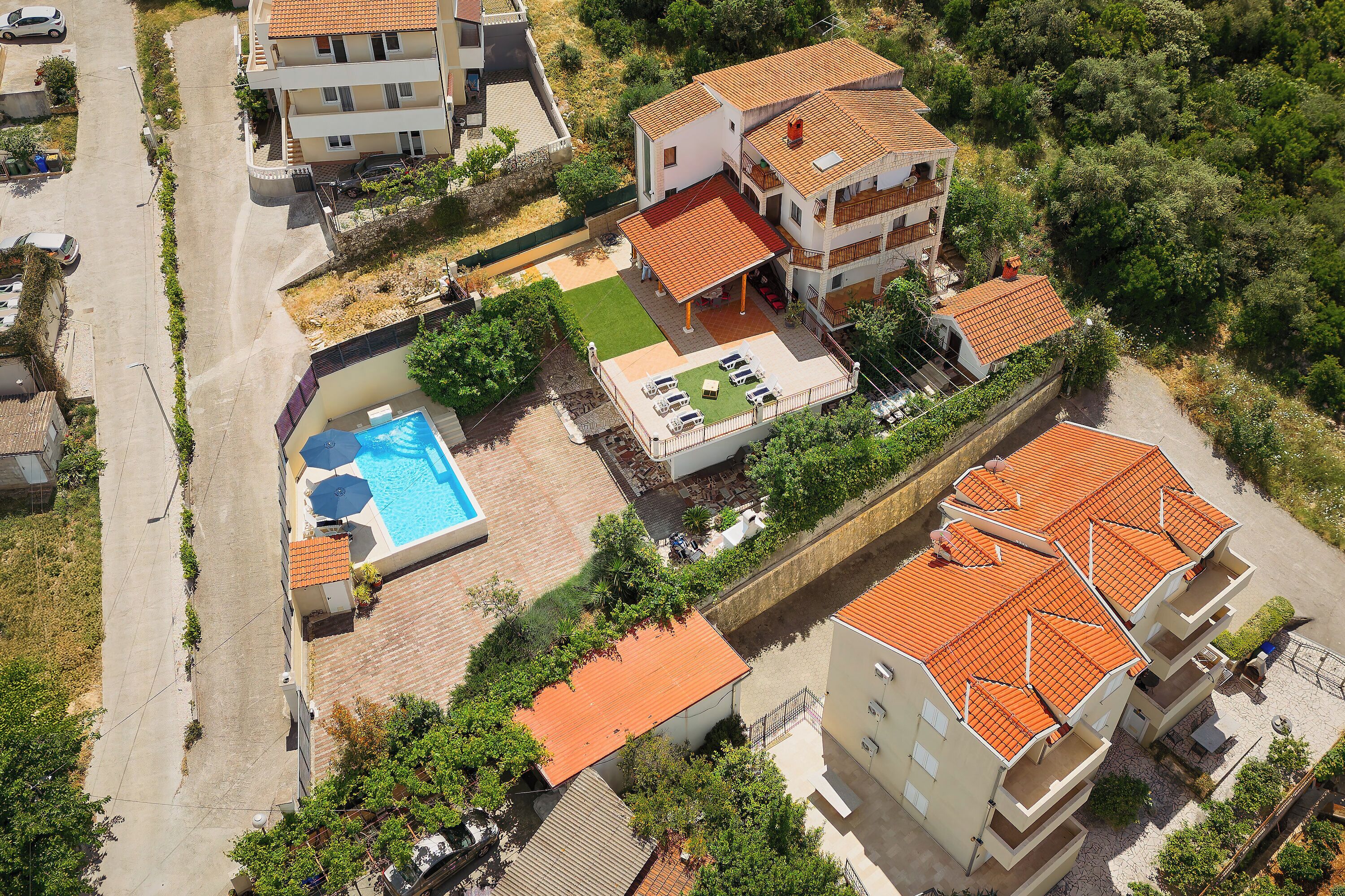 An aerial view of a residential area with multiple buildings, a swimming pool, and a well-maintained garden.