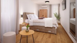 A modern bedroom with a bed, bedside table, and a small round table with a vase of flowers. - Sun Spalato Villa Alisa (Mastrinka)