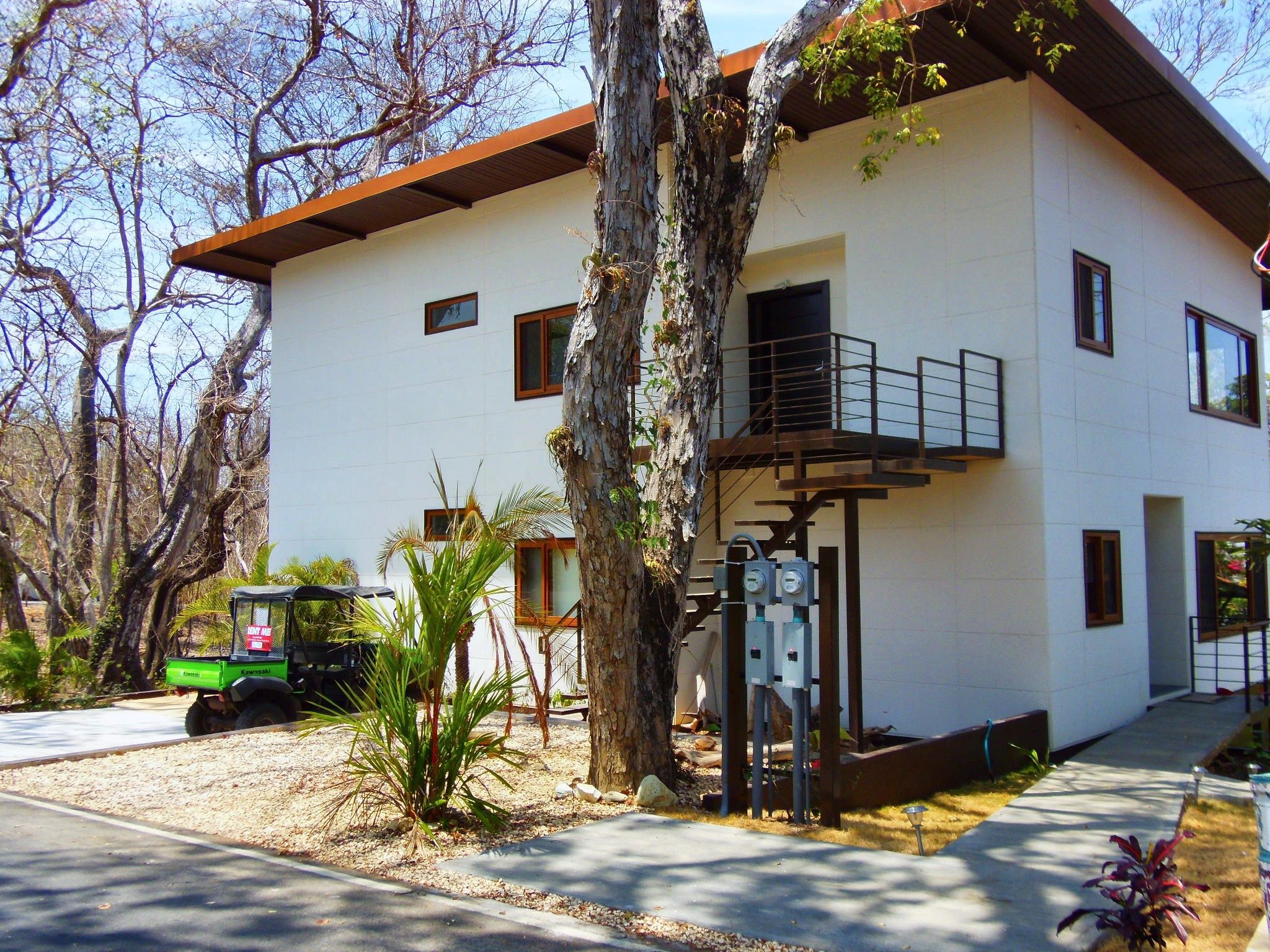 A two-story building with a balcony, a driveway, and a parked vehicle.
