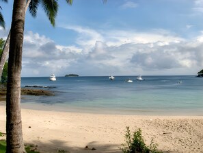 A beach with clear water, boats, and a distant island. - Gemini Villas – Gemini II (Contadora Island)