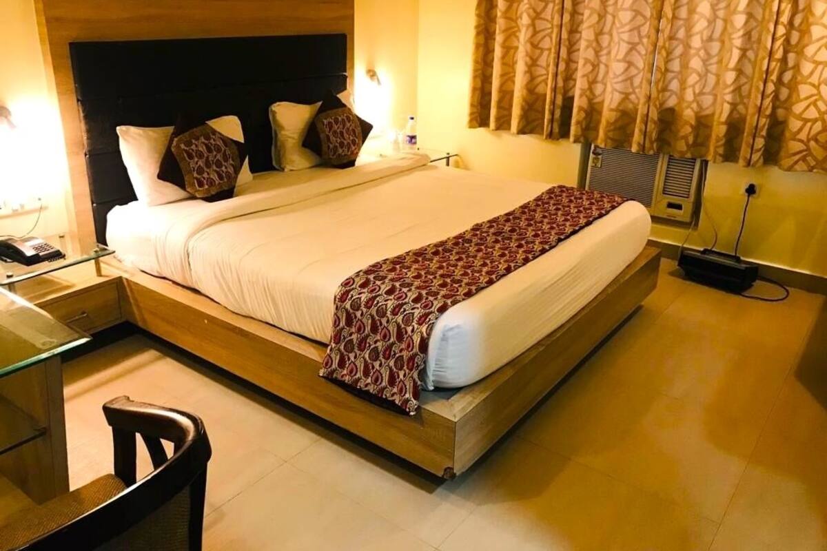 A hotel room with a large bed, bedside tables, a desk, and a chair.