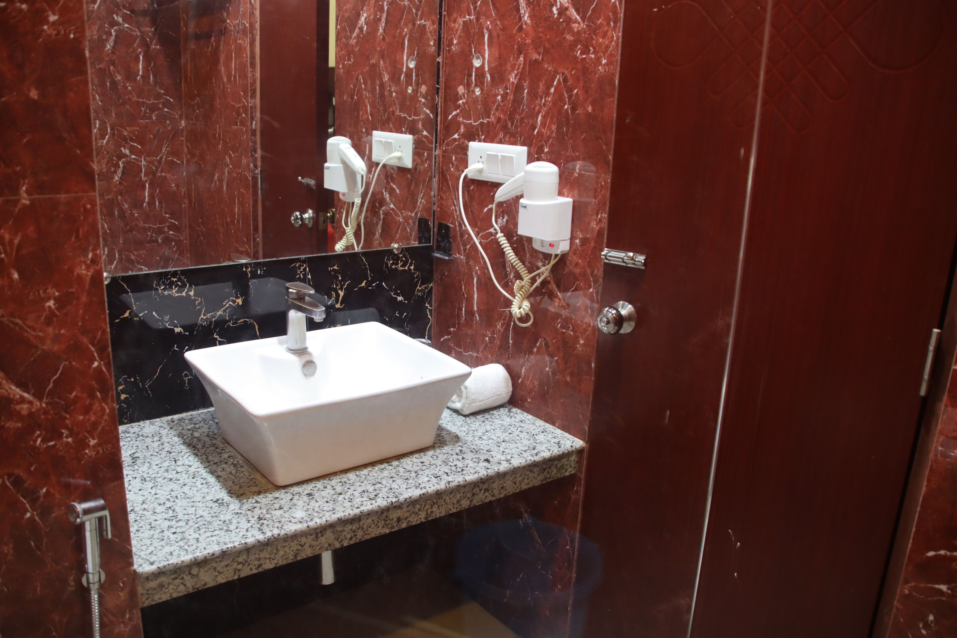 A bathroom with a marble vanity, a sink, a towel, and a mirror.
