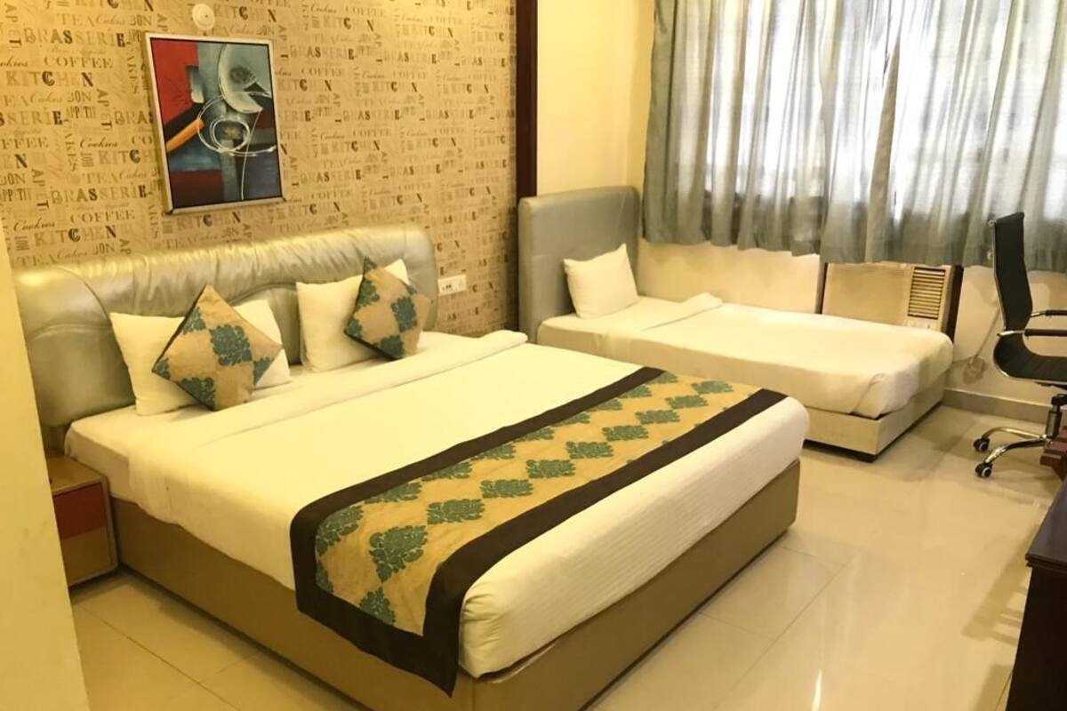 A hotel room with a large bed, a smaller bed, a desk, and a chair.