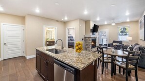 A modern kitchen with granite countertops, a dishwasher, and a dining area with a table and chairs.