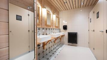 Une salle de bain moderne avec un lambris en bois, trois lavabos et un carrelage au sol.