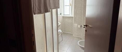 A bathroom with a shower, toilet, and sink.