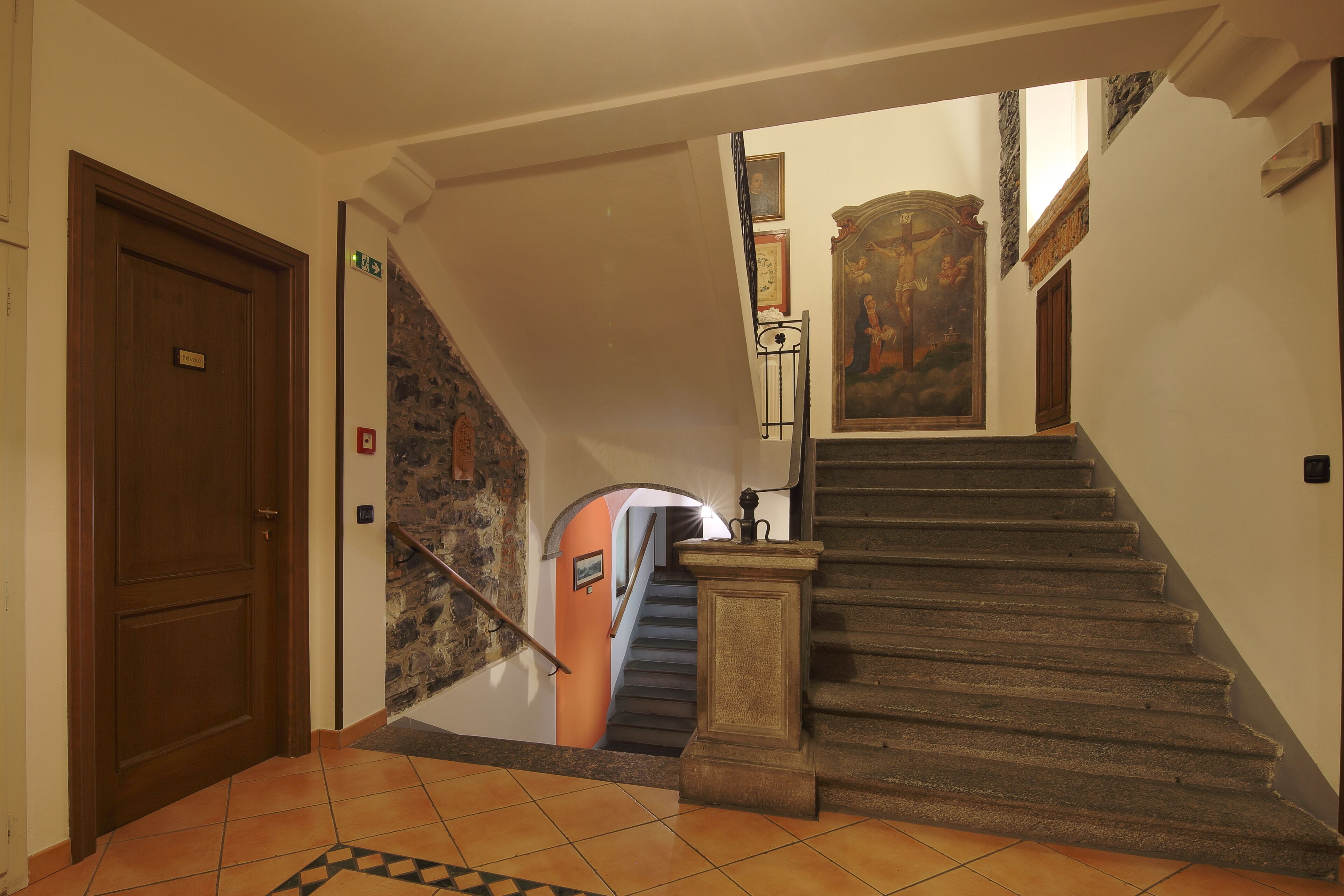 Eine Treppe mit Steinbalustrade, die zu einer niedrigeren Ebene führt, eine Holztür links und eine Wand mit einem gerahmten Gemälde.