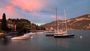 A marina with several sailboats docked, surrounded by buildings and hills. - Hotel La Pergola  (Bellagio)