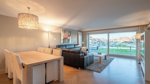 Een moderne woonkamer met een eettafel, bank en een groot raam met uitzicht op de stad.