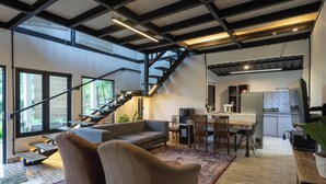 A modern living space with a staircase, a dining area, and a kitchen. - Lingga Garden House (Cisarua)