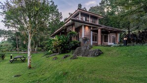 A two-story house with a brick exterior, a covered porch, and a stone fireplace. - Lingga Garden House (Cisarua)