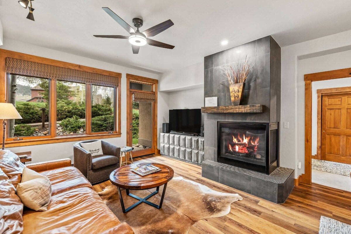 Una sala de estar con chimenea, sofá de cuero y televisor.